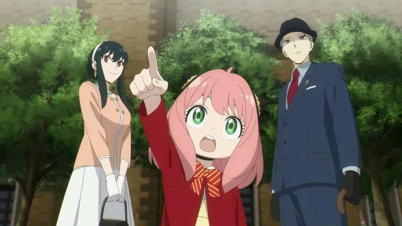 The Forger family from the anime series Spy × Family, featuring Yor, Anya, and Loid, standing outdoors. Anya is pointing up with an excited expression.