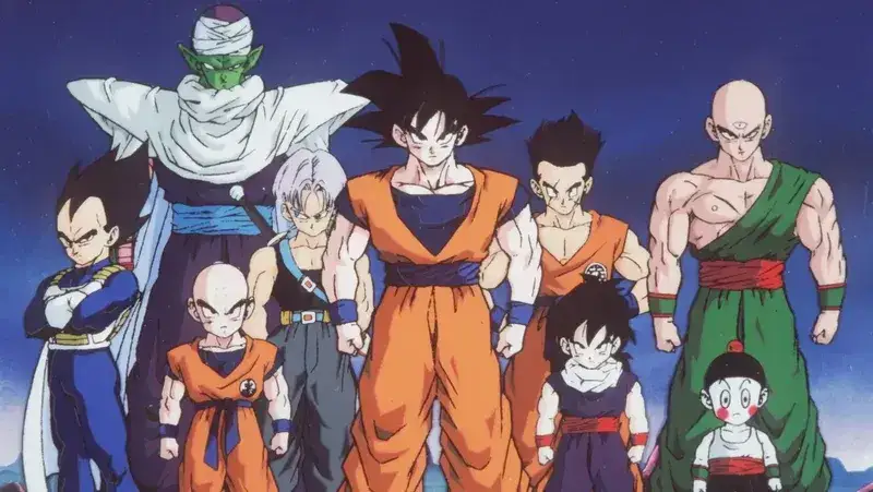 A group of prominent characters from the Dragon Ball Z anime series stand together. From left to right, the characters shown are Vegeta, Krillin, Piccolo, Trunks, Goku, Gohan, Tien Shinhan, and Yamcha. They are depicted in their respective martial arts uniforms against a blue and purple sky background. 