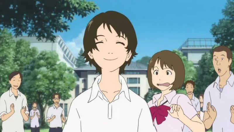 An anime scene from the film The Girl Who Leapt Through Time shows the main characters in a schoolyard setting. In the foreground, a boy with brown hair, Chiaki Mamiya, smiles broadly. To his right, the protagonist, Makoto Konno, makes a comical, wide-mouthed expression. Several other students are visible in the background, including another boy on the far right with a surprised look on his face. The background features school buildings and green trees under a blue sky. 