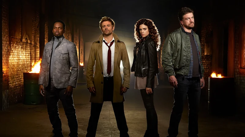 Four cast members from the TV series Constantine, including actor Matt Ryan as John Constantine, stand in an alleyway with fire barrels in the background.
