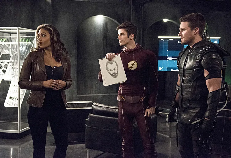 A scene from The Flash TV show features Ciara Renée, Grant Gustin, and Stephen Amell, where Grant Gustin holds a drawing of a suspect. The scene is from the "Legends of Today" crossover episode. 